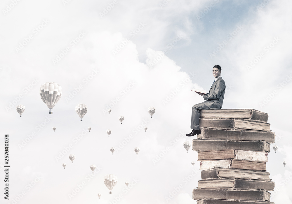 Man student reading book and aerostats flying around in air Man student reading book and aerostats flying around in air