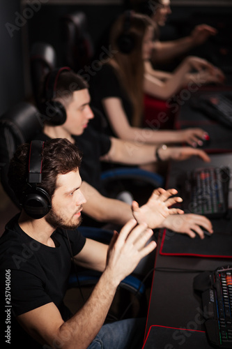 Young female and male gamers playing video game while spending weekend leisuretime at pc gaming club, focused serious people behind pc monitor at dark room. Entertainment or addiction concept © alfa27