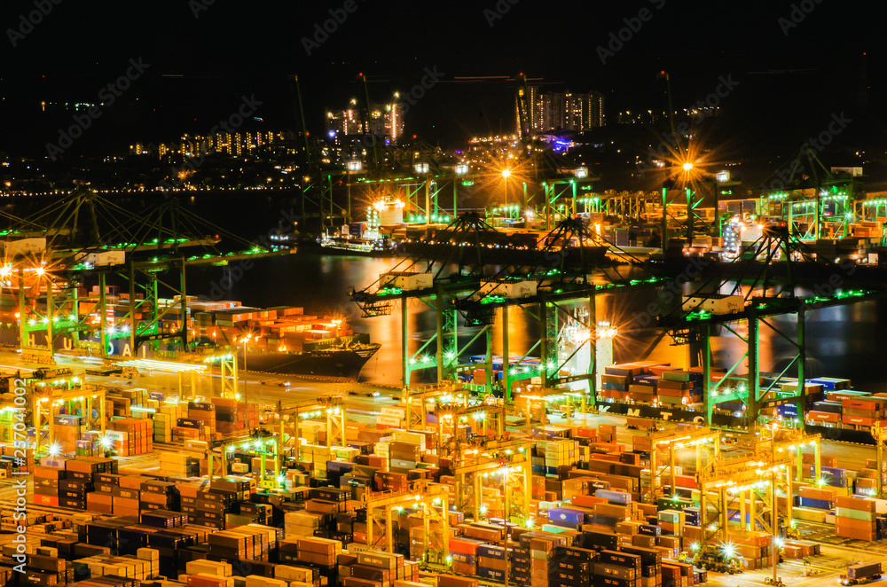 Fototapeta premium Beautiful aerial view of busiest Asian cargo port with hundreds of ships loading export and import goods and thousands of containers in harbor with the downtown core background