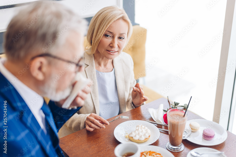 pleasant good looking woman looking at the man who is wiping his mouth with a paper napkin. close up photo