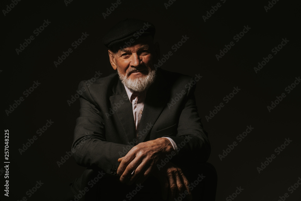 Serious middle-aged man with folded arms and a deadpan expression posing in front of a dark background
