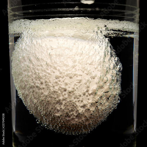 concept white egg covered with bubbles in glass with vinegar close-up