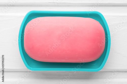 Obraz na plátně Pink soap in a blue soap dish on a white wooden background