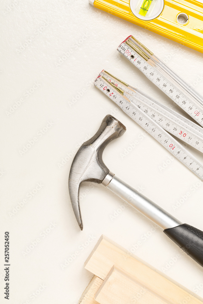 Construction tools and wooden strips on white plaster background
