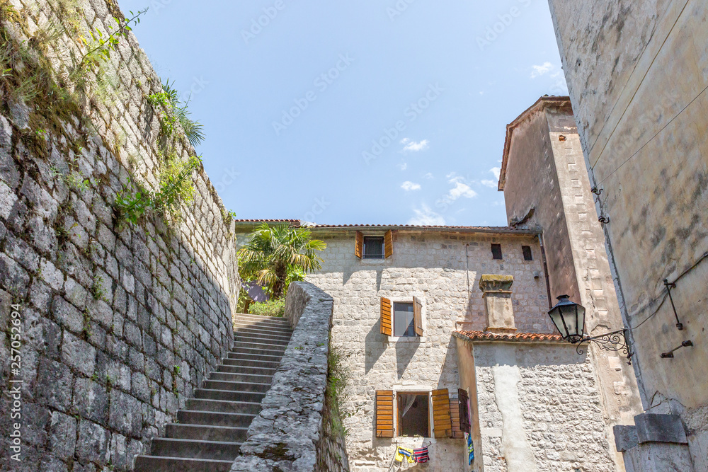 A narrow dead end alley with a staircase and stone doorway leading to apartments in the medieval old town center of Kotor, Montenegro.