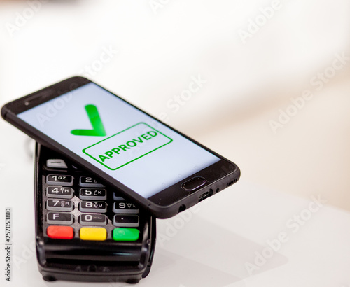 POS terminal, Payment Machine with mobile phone on store background. Contactless payment with NFC technology