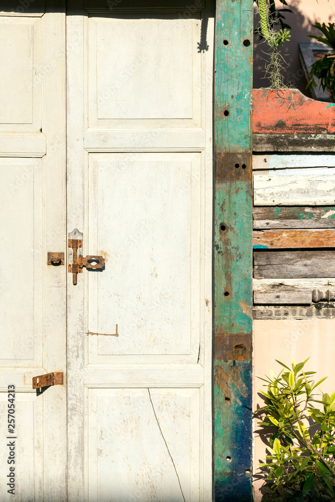 An old closed rustic wooden front door with a rusty lock