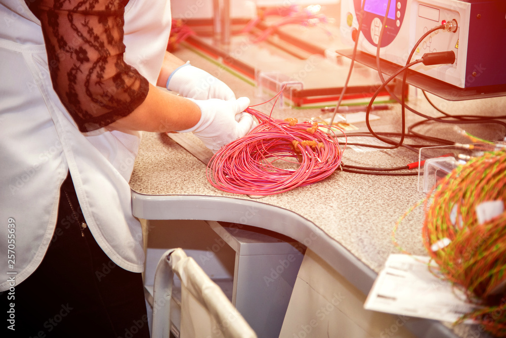 the worker tests for the definition of quality part of the wiring for cars at a modern plant in a production workshop