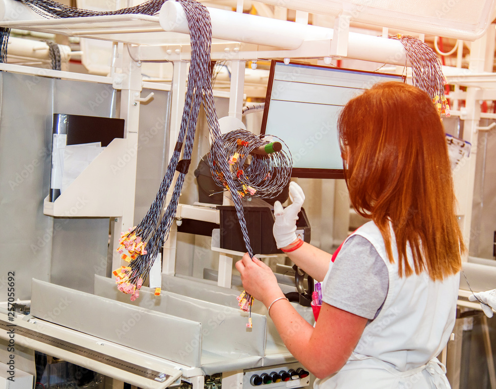 the worker tests for the definition of quality part of the wiring for cars at a modern plant in a production workshop