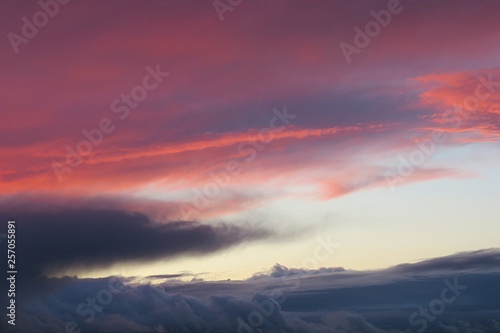 Beautiful burgundy pink sunset background with dark clouds on horizon, natural sunset background