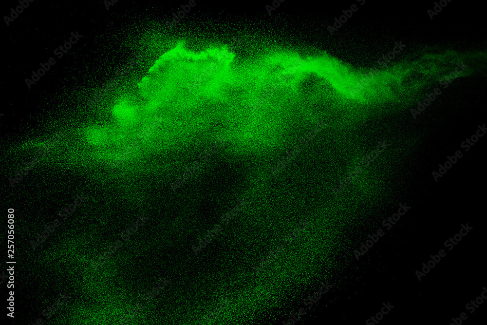 Green dust particles explosion on black background. Color powder dust