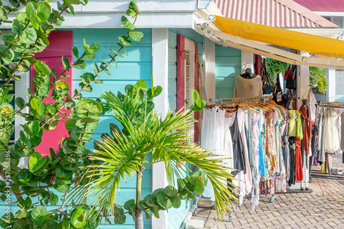Caribbean island clothing store/boutique for ladies. Clothes on display on rolling garment racks and handbags in background.