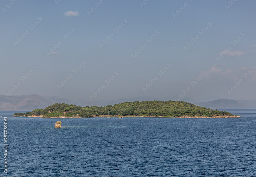 View of a small green islet, in the middle of a beautiful landscape and a calm sea View of a small green islet, in the middle of a beautiful landscape and a calm sea