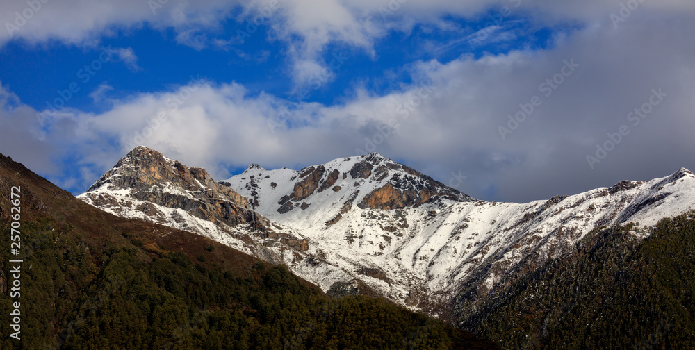 Mountain Landscape, Snow Covered Mountain Range - Daocheng Yading Nature Reserve. Ganzi, Garze, Kham Tibetan area of Sichuan Province China. Dramatic lighting during sunset, Clouds and Blue Sky