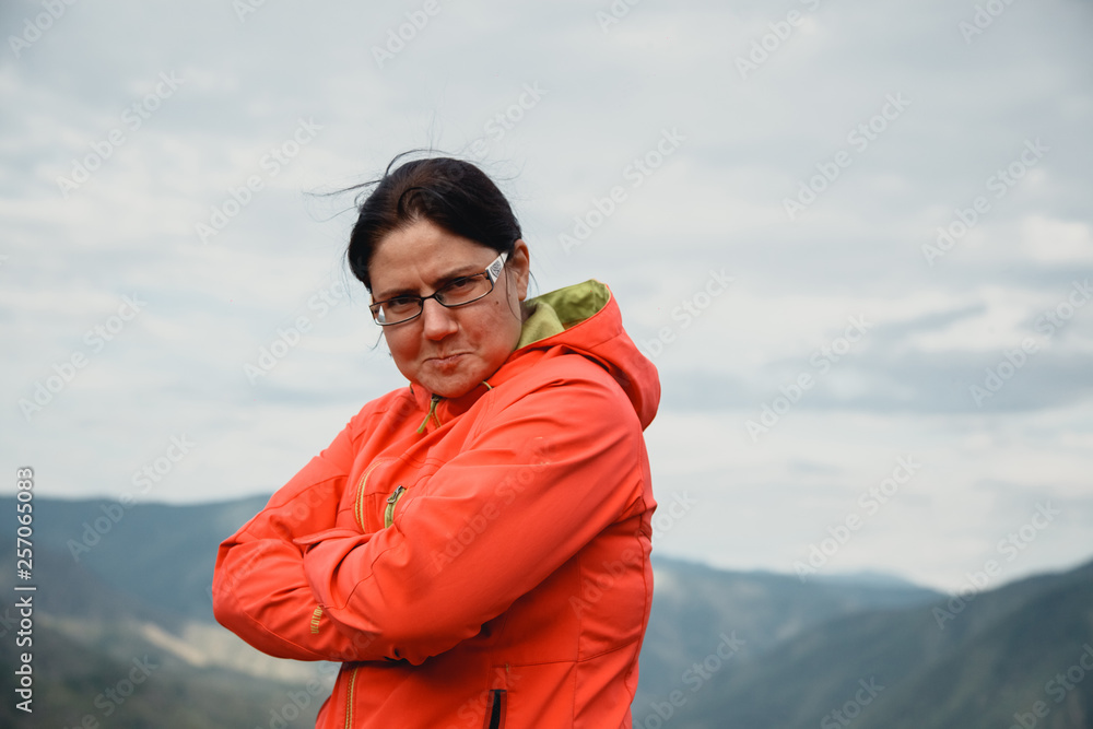 Girl in a red jacket sitting on the mountain. Enjoys the beautiful view around. comic face