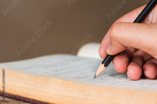 close-up of hand writing circle in old book with wooden pencil