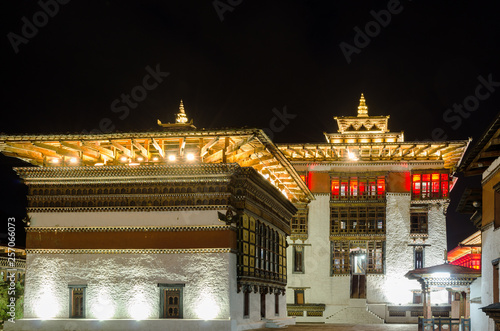 Tashichho Dzong at night, Thimphu, Bhutan. Towers topped by triple-tiered golden roofs. 