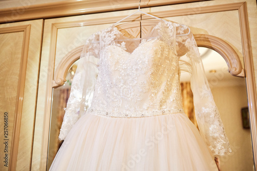 beautiful wedding dress hanging in the room, woman getting ready before ceremony