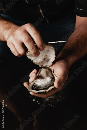 hands open the oyster with a knife photo