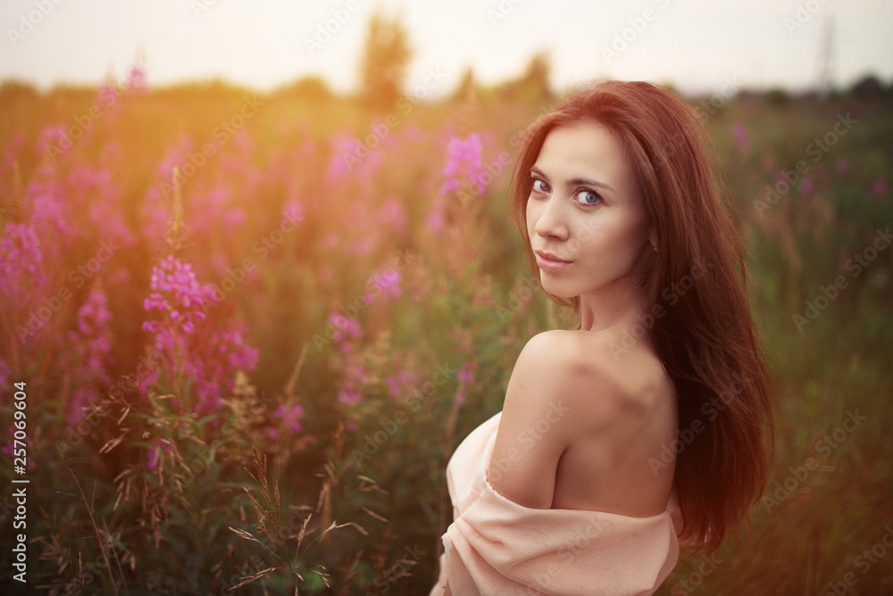 beautiful woman with brunette hair in light clothes posing in flower field on background beautiful woman with brunette hair in light clothes posing in flower field on background