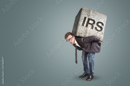 Businessman carrying a heavy stone with the letters IRS on it  photo