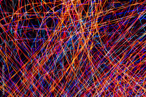 Colorful light painting abstract long exposure image with pink, blue, red and yellow lines on a black background