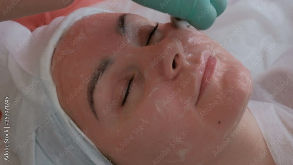 Beautiful girl on a cosmetological procedure in a beauty salon. The hands of a beautician spend electrodes on the skin of the face of a young woman. The use of galvanic current. Hardware cosmetology. Beautiful girl on a cosmetological procedure in a beauty salon. The hands of a beautician spend electrodes on the skin of the face of a young woman. The use of galvanic current. Hardware cosmetology.