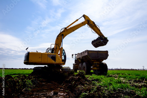 Excavator is loading a truck with ground on building site