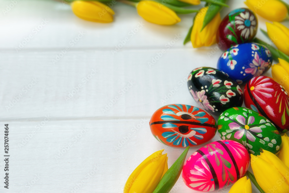 Easter eggs and yellow tulips on wooden background.
