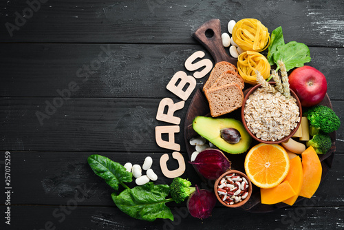Foods high in carbohydrates: bread, pasta, avocado, flour, pumpkin, broccoli, beans, spinach. The concept of healthy eating. On a black background.