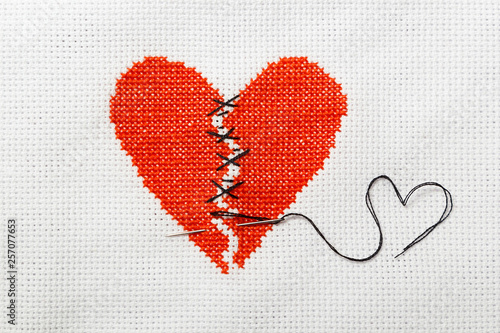 Canvas Print The broken red heart is threaded with black threads
