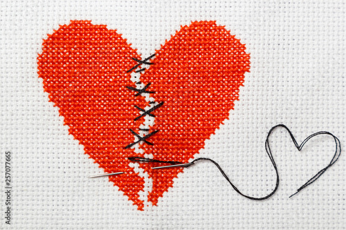 Fotografie The broken red heart is threaded with black threads