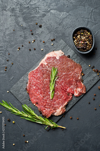 Beef BBQ steak on a stone Board with rosemary. Black background, top view, space for text