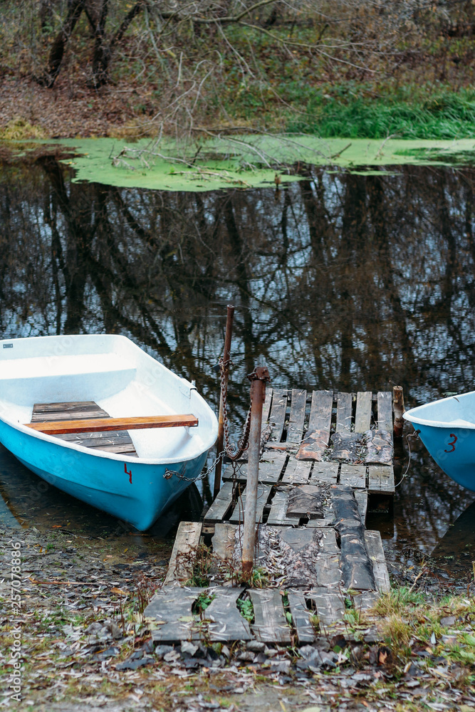 self-made, wooden pier from the old boards on the lake, near are the boats, the river in the mud, duckweed self-made, wooden pier from the old boards on the lake, near are the boats, the river in the mud, duckweed