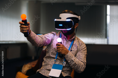 Konstfotografi Bearded man in motion wearing vr goggles and playing video game at the dark room