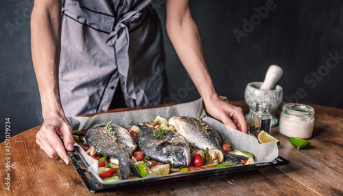 Photography mother cooks dinner for the whole family, bakes dorado fish