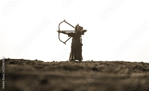 Medieval battle scene with cavalry and infantry. Silhouettes of figures as separate objects, fight between warriors on dark toned foggy background. Night scene. Selective focus