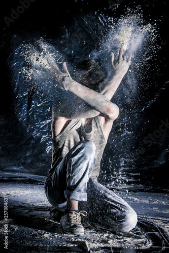 cool dirty сhinese guy dancer in style of bboying doing complex tricks on floor in Studio filled with flour on black background. concept of space dance on surface of planet moon