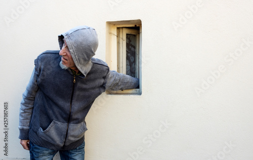 Burglar or thief or robber is stealing with arm through the small window