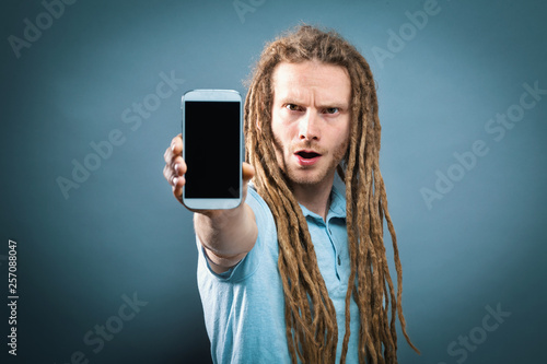 Young man holding out a cellphone in his hand