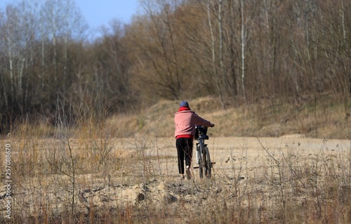 woman riding bicycle in forest, Poland © Robert
