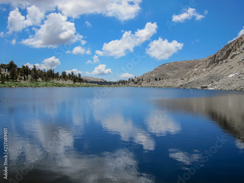 Placid lake in high sierra nevada mirroring deep blue sky and clouds