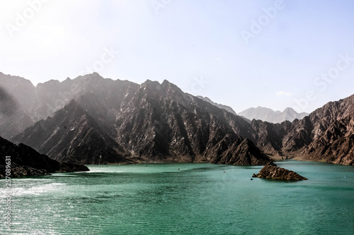 Geological landscape of hatta dam characterised by dry and rocky mountains and lake between scenery mountains, water reservoir Between hills in Dubai, United Arab Emirates