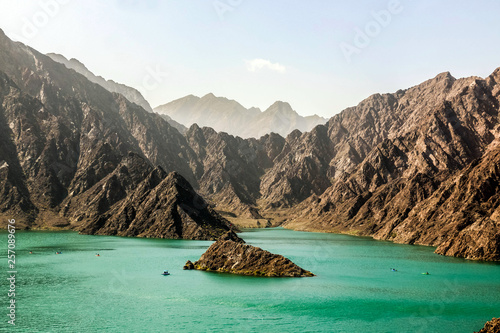 Geological landscape of hatta dam characterised by dry and rocky mountains and lake between scenery mountains, water reservoir Between hills in Dubai, United Arab Emirates