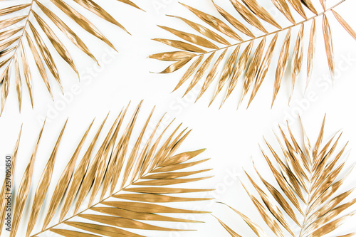 Gold tropical palm leaves on white background. Flat lay, top view minimal concept.