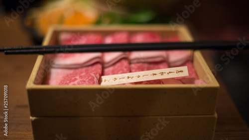 Shabu shabu slices beef meat serving in bento box with chop sticks closeup