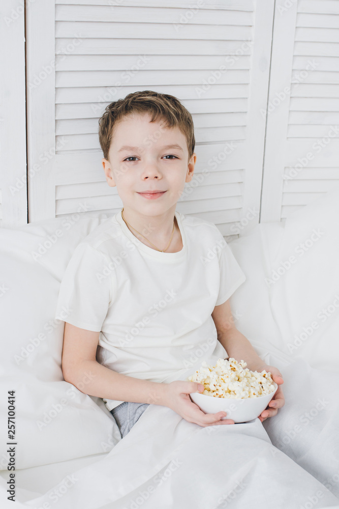 Boy eating popcorn sitting in bed