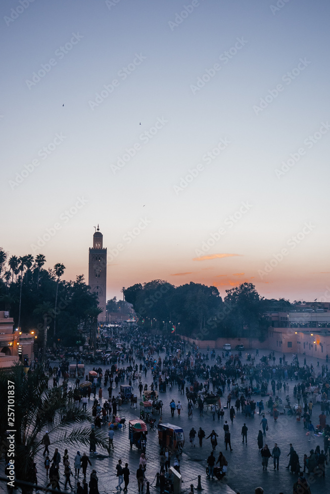 A beautiful view of the famous minaret as well as the bustling activity in the streets of Marrakech at dusk.