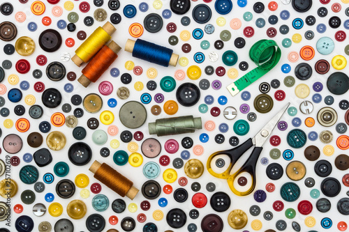 background - multicolored buttons and sewing accessories on a white surface