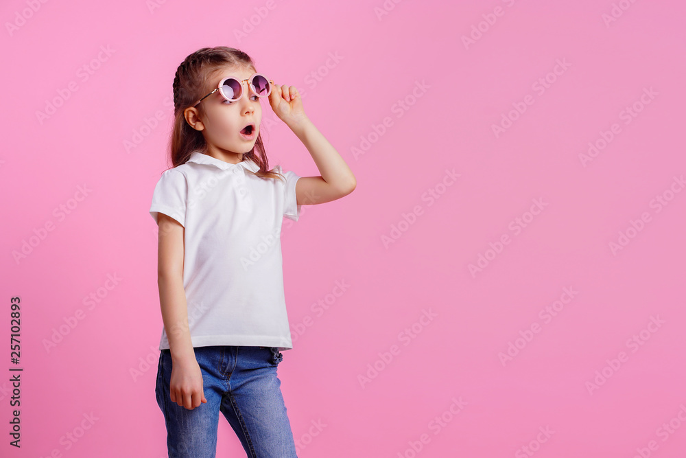 Portrait of beautiful smiling cute model in trendy round sunglasses. Casual 7 y.o. girl posing isolated on pink background. Portrait of beautiful smiling cute model in trendy round sunglasses. Casual 7 y.o. girl posing isolated on pink background.